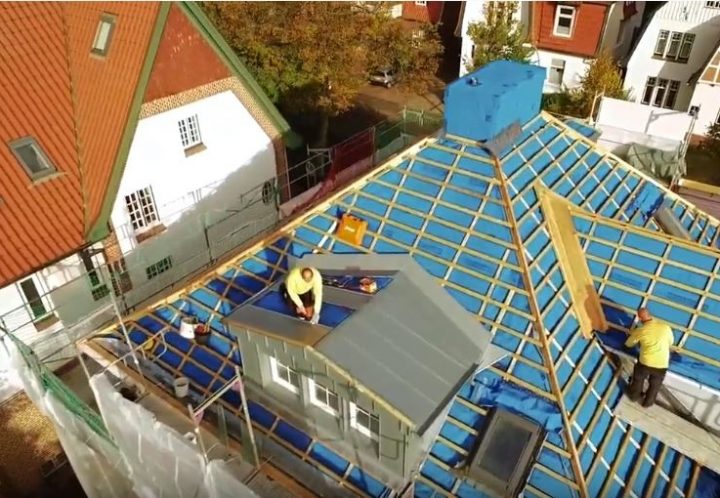 Dachdecker bei der Sanierung eines Hauses, das mit einem Metalldach eingedeckt wird